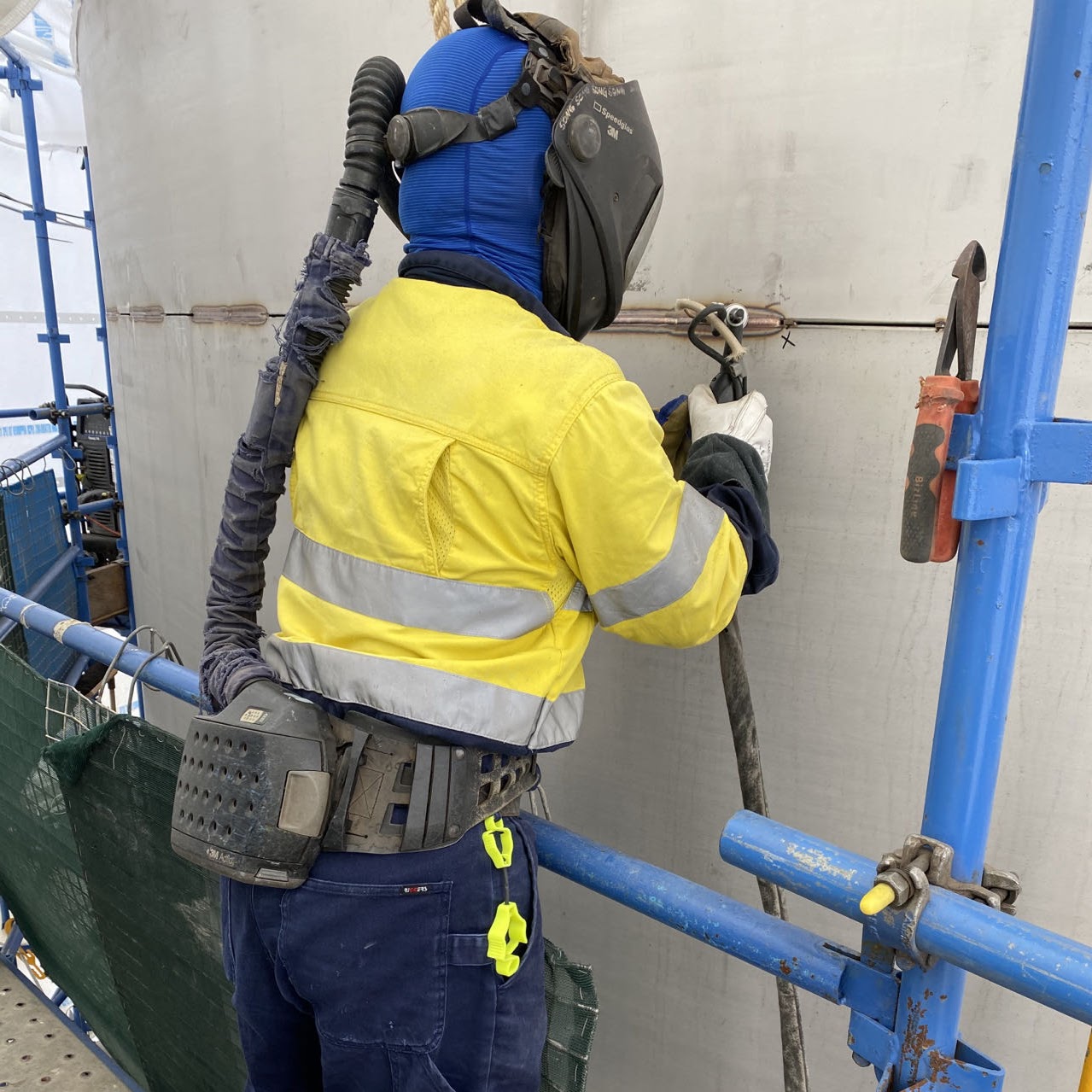 Welder working on a tank from suspended access